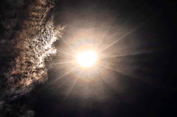 Solar Eclipse With Rays And Clouds